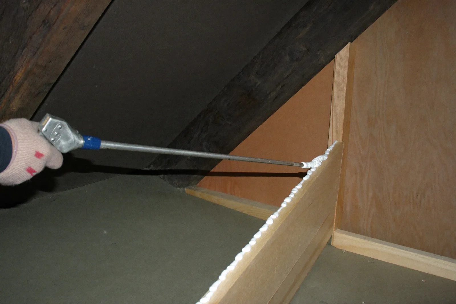 Foam applicator gun sealing a gap in attic framing