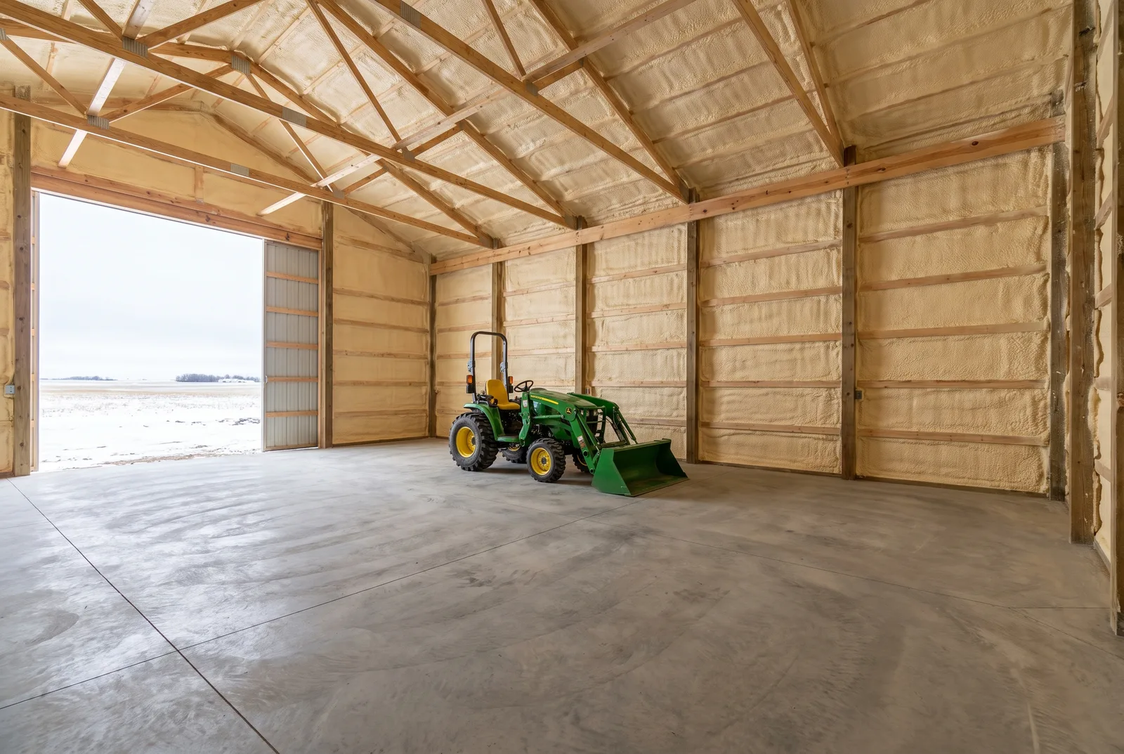 Pole barn interior with an even layer of spray foam on the walls and roof deck